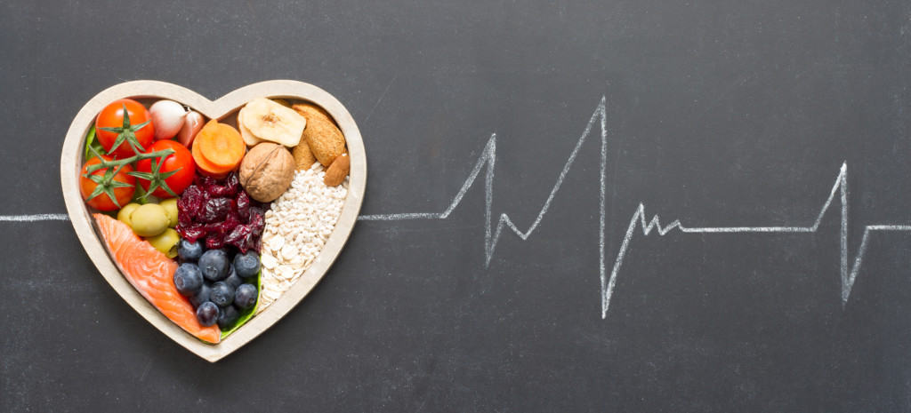 heartbeat pattern drawn on chalkboard with heart-shaped bowl filled with healthy food