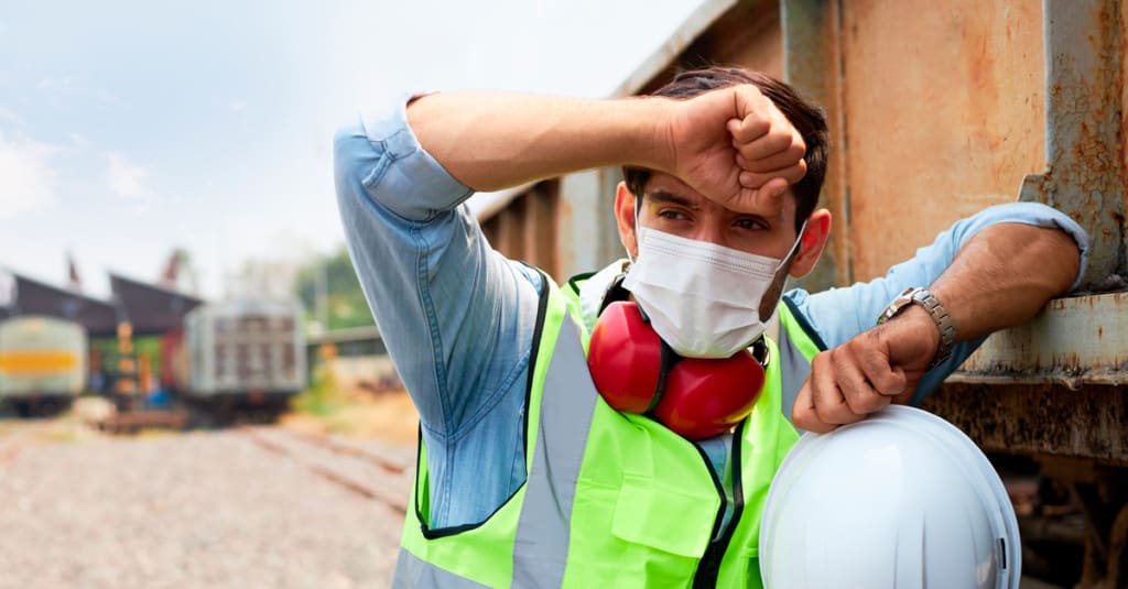 Construction worker pausing to wipe brow on a hot day.