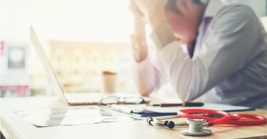 workplace burnout, doctor at desk with head in hands