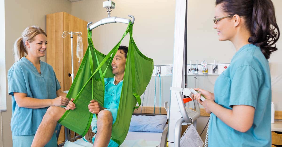 Nurses help transfer a patient with a mechanical lift.